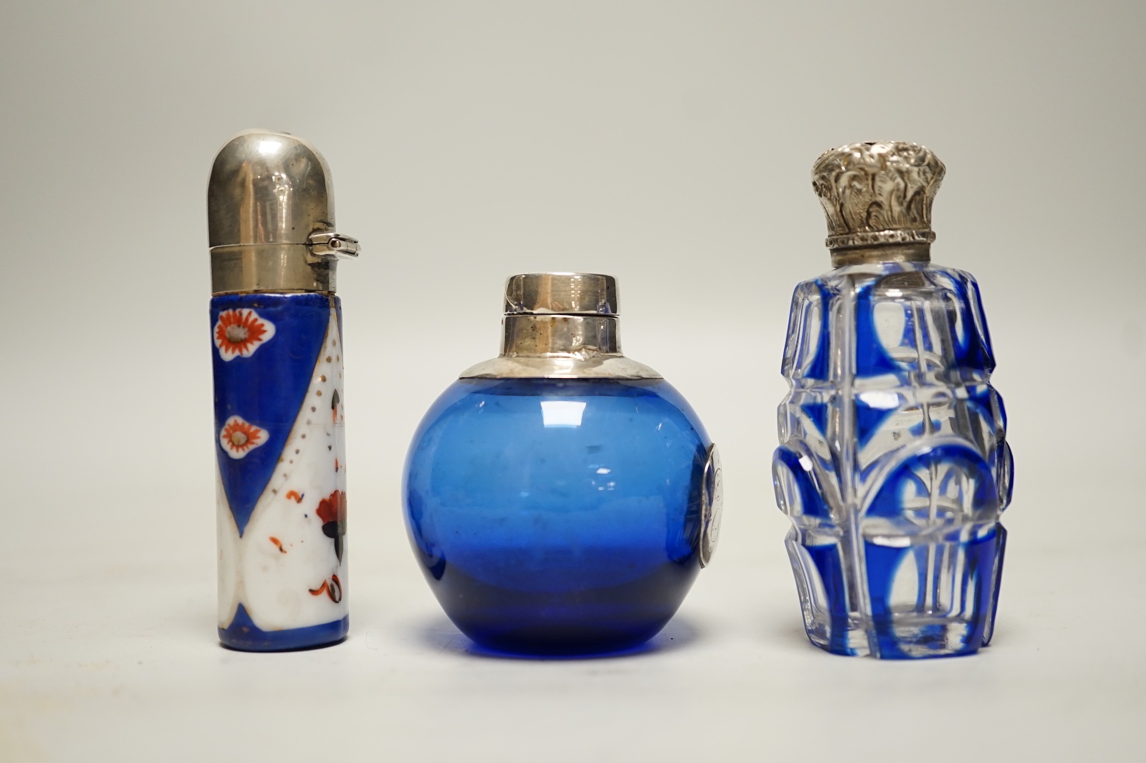 Three assorted silver or white metal mounted glass or porcelain scent bottles, tallest 78mm.